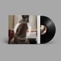Großes "Ö" auf unscharfem Foto einer Person in einem Raum. Rechts ist eine schwarze Vinyl-Schallplatte zu sehen., LP