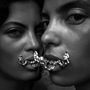 Zwei Gesichter nahe beieinander, verbunden durch eine kunstvolle, metallische Kette über den Lippen., LP