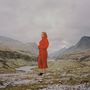 Kein Text vorhanden. Eine Person in rotem Outfit steht in einer bergigen Landschaft mit einem Fluss im Hintergrund., LP