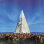 Ein großes, weißes, verwittertes Pyramiden-Denkmal vor einem strahlend blauen Himmel und blühenden gelben Sträuchern., LP