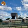 "THE HIGH SPAN Blöttenberg. Eine unterirdische Laus." Ein modernes Gebäude mit Zaun, blauer Himmel und Wolken., LP