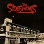Der Text "The Sideshows" ist in roter, auffälliger Schrift zu sehen. Darunter ein historisches Gebäude mit bunten Schildern., LP