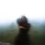 Ein verschwommenes Bild einer Person in Nebel, die sich bewegt. Die Umgebung ist unscharf und düster.