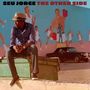 Oben steht "SEU JORGE THE OTHER SIDE". Ein Mann mit Hut sitzt auf einem Container vor einer bemalten Wand., CD
