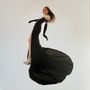 Keine sichtbaren Texte. Eine Person in einem langen, schwarzen Kleid mit weißen Details und hochgeschlitztem Rock., LP