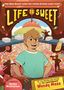 "LIFE IS SWEET" steht in großen Buchstaben. Ein lächelnder Junge steht vor einem Hintergrund voller Süßigkeiten.