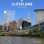 Text: CLEVEVLAND A KEEPSAKE, Gary J. Sikorski. Skyline von Cleveland mit einem Fluss, auf dem zwei Personen in einem Kajak paddeln., Buch