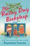 "The Rainy Day Bookshop: A novel, RaeAnne Thayne." Illustration einer Buchhandlung bei Regen mit zwei Personen und einem Regenschirm.