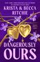 „KRISTA & BECCA RITCHIE, DANGEROUSLY OURS.“ Goldene Herz-Medaillons an Kette, lila Blumen und Zweige.