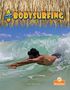 Text: "BODYSURFING", "Catch a Wave", "Kerri Mazzarella", "Branches". 
Ein Surfer gleitet durch eine Welle unter einem Strohdach., Buch