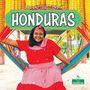 „Life and Traditions in Honduras“. Frau in rotem Kleid sitzt auf bunter Hängematte, lächelt, Hintergrund voller Maiskolben., Buch