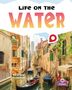 Text oben: "LIFE ON THE WATER". Unten: "HEATHER C. HUDAK". Szene: Ein Kanal mit Gondeln zwischen alten Gebäuden., Buch