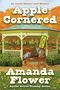 „Cover to be revealed soon!“, „APPLE CORNERED“, „by Amanda Flower“. Unten ein stilisiertes Logo mit einem blauen Buch.