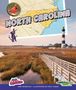 Text: North Carolina, Ann Heinrichs, Illustrated by Matt Kania. Karte und Leuchtturm in einer Landschaft mit Holzsteg., Buch