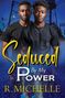 "Seduced By My Power" in gelb und weiß; "R. Michelle" darunter. Zwei Männer in schwarzen T-Shirts im Hintergrund., Buch