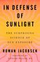 Cover eines Buches: „IN DEFENSE OF SUNLIGHT“ von Rowan Jacobsen. Orange-rosa Hintergrund mit Sonnenstrahlenmuster., Buch