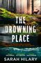 „THE DROWNING PLACE“ in weißen Buchstaben. Darunter: „AN INEXPLICABLE MURDER“ in Orange. Waldszene mit laufendem Hirsch.