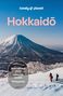 "Hike national parks, Hokkaidō wildlife, Skiing guide." Zwei Wanderer vor verschneitem Berg unter blauem Himmel., Buch