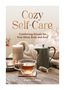 Titel: Cozy Self-Care. Untertitel: Comforting Rituals for Your Mind, Body and Soul. Autor: Sophie Golding. Eine Teetasse, Teekanne, Kerzen und eine Decke., Buch