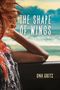 Text: "The Shape of Wings" und "Ona Gritz". Frau blickt aus Autofenster Richtung Meer, ihre Haare wehen im Wind., Buch