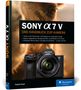 Buchtitel "Sony α7 V – Das Handbuch zur Kamera". Vorderansicht einer Kamera auf unscharfem Hintergrund., Buch