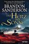 "Brandon Sanderson: Das Herz der Sonne. Ein Kosmeer-Roman." Eine Person steht auf Felsen mit Blick auf eine schwebende Stadt., Buch