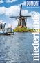 „DUMONT Reise-Taschenbuch Niederlande“. Windmühle, blauer Himmel, Boot im Wasser, niederländische Flagge., Buch