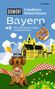 Buchtitel: "Unnützes Reisewissen Bayern", mit Dackel, Brezel und bayerischem Schloss vor Alpenhintergrund., Buch