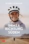 Titel: Immer Richtung Süden; Untertitel: 20.000 Kilometer mit dem Rad; Eine Frau mit Helm lächelt, im Hintergrund Wüste.