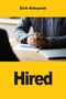 Text "Eichi Kobayashi" oben und "Hired" unten. Dazwischen sind gefaltete Hände auf einem Tisch mit Laptop., Buch