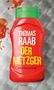 "THOMAS RAAB DER METZGER KRIMINALROMAN" auf einer roten Ketchupflasche mit grünem Deckel, Tomatensauce spritzt heraus., Buch