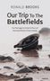 Riesige Buchstaben: "Our Trip To The Battlefields". Verlassenen Helm am sandigen Strand mit Steinen., Buch