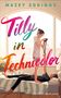 „MAZEY EDDINGS, Tilly in Technicolor“. Eine Frau hält eine Kamera; ein Mann liegt auf einem Bett in einem hellen Raum.