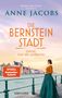 „Die Bernstein Stadt“ von Anne Jacobs. Frau in historischem Kleid blickt auf farbenfrohe städtische Uferpromenade., Buch
