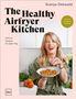 Ein Buchcover mit dem Titel "The Healthy Airfryer Kitchen" von Svenja Ostwald. Eine Frau hält einen Teller mit knusprigen, braunen Häppchen und lächelt in einer Küche., Buch