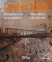 Dieter Nuhr: Woanders ist überall. Eine Brücke über einem Fluss, in warmen, erdigen Farbtönen., Buch