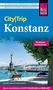 "City|Trip Konstanz" und andere Sehenswürdigkeiten. Uferansicht mit Bäumen, Statue, Sitzbänken und Schiff im Hintergrund., Buch