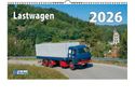 "Lastwagen 2026". Ein blauer Lastwagen auf einer kurvigen Straße, umgeben von üppigem Grün und einem Dorf im Hintergrund.