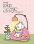 "CocoWyo Cozy Planner, Undated monthly & weekly planner" in verspielten Buchstaben. Ein Hund liest im Sessel, daneben eine topfgepflanze., Buch