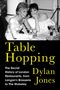 „Table Hopping“; Autor: Dylan Jones. Zwei elegant gekleidete Frauen bei einem Tischgespräch, Getränke und Lachen.