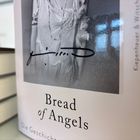 "Bread of Angels" steht unter einem unscharfen Schwarzweißfoto von einer Person in einem weißen Kleid.