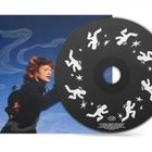Eine CD mit weißen Figuren und Sternen. Im Hintergrund ein verschwommenes Porträt vor blauem Hintergrund.