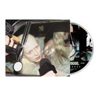 Eine Person mit hellem Haar wird durch ein Autofenster von Mikrofonen umgeben, daneben eine CD mit schwarz-weißem Design.