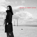 Text: "DEDICATO AD ALBERTO COCUZZA". Schwarz-weiß Bild einer Frau im Mantel, eine einsame Landschaft mit Sand und Wolken.