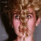 „blondshell“ oben links, „violins“ unten links. Frau mit lockigem, blondem Haar verdeckt teilweise ihr Gesicht.