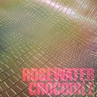 ROSEWATER CROCODILE in pink auf Textur, die an Krokodilhaut erinnert, mit sanften, grünlichen und rosafarbenen Tönen.