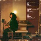 Texte: Songtitel-Liste. Frau mit lockigem Haar sitzt vor einem Keyboard, eine warme Lampe scheint hinter ihr. Vintage-Stil.