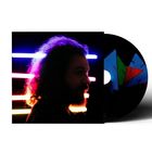 Ein Porträt von der Seite beleuchtet von bunten Neonlichtern, daneben eine CD mit buntem geometrischem Design.
