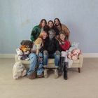 Eine Gruppe von sechs Personen sitzt auf einem Sofa, umringt von vielen Kuscheltieren.