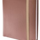 Braunes Notizbuch mit Kunstlederoptik, gesichert durch ein beige Gummiband.